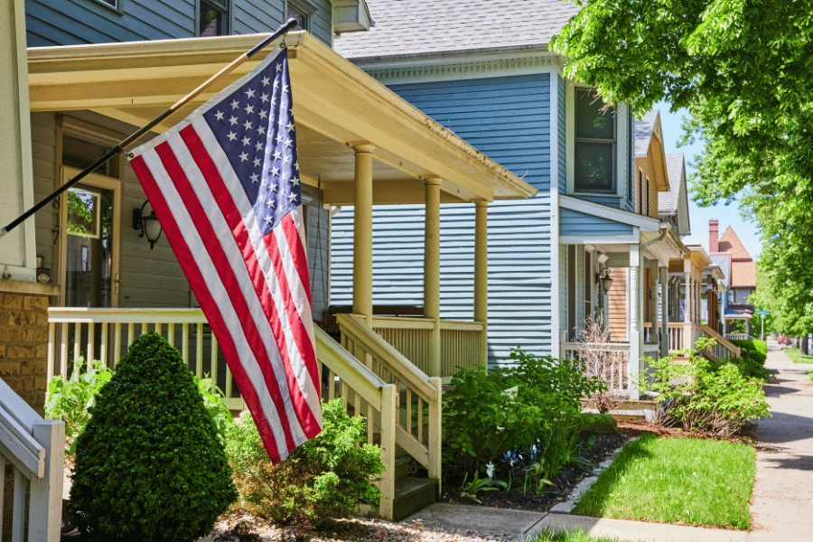 quiet suburban street with American flag hanging on the front porch of one home